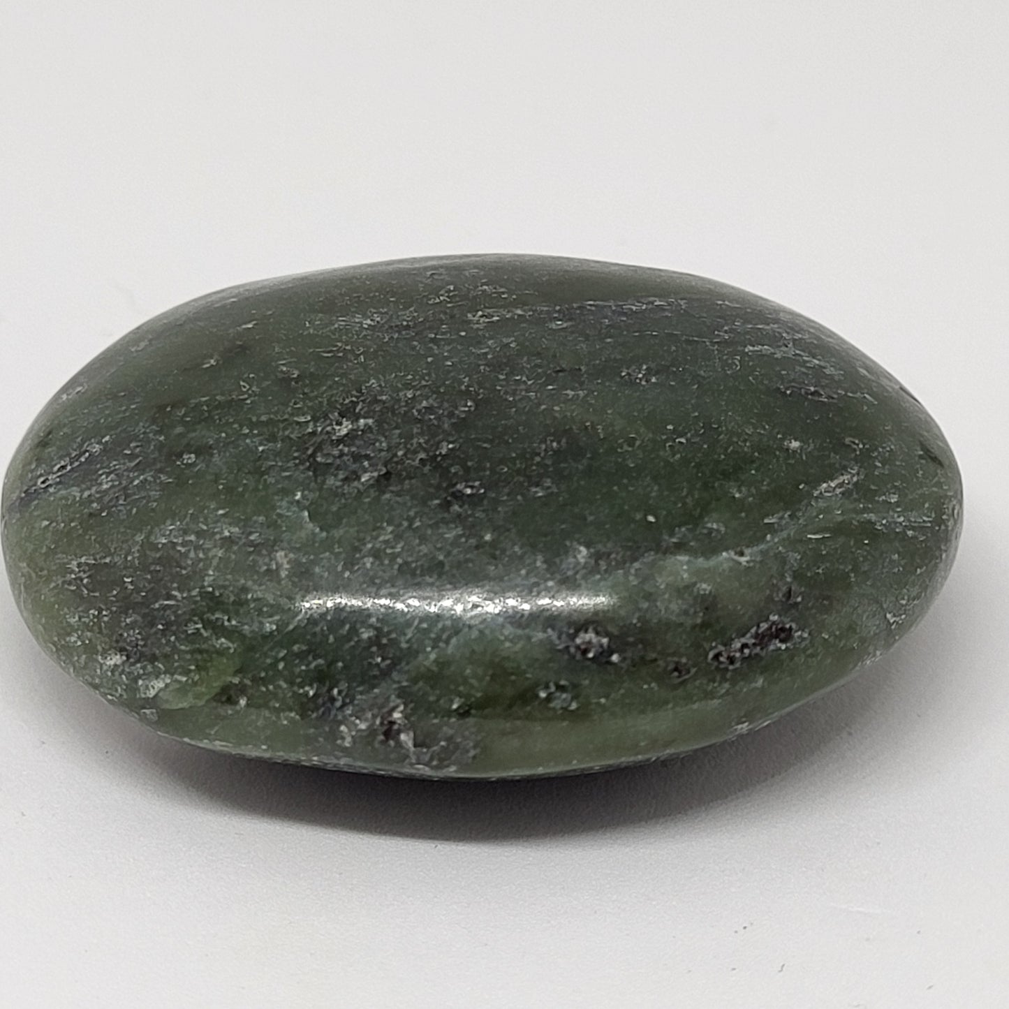 A polished nephrite jade palm stone on a white background.
