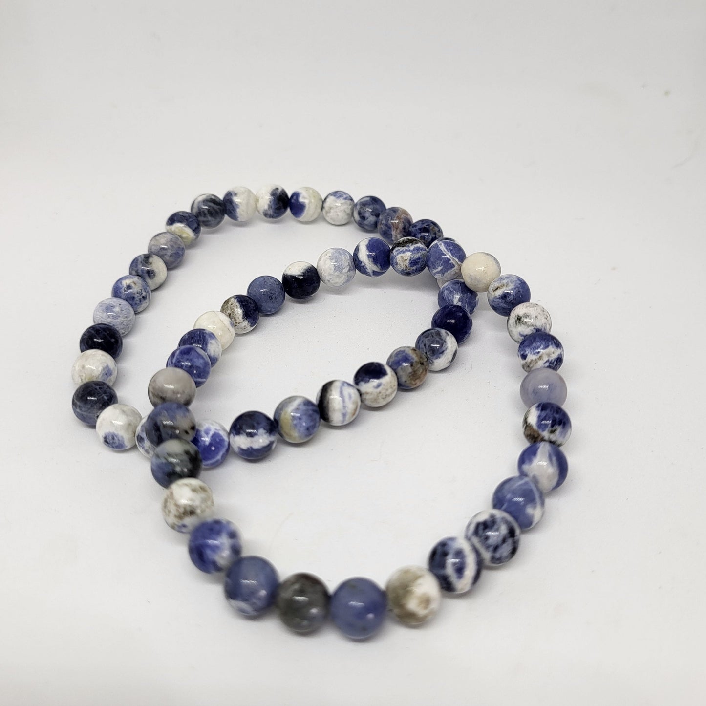 A blue and white sodalite bracelet with 8mm beads, displayed against a white background.