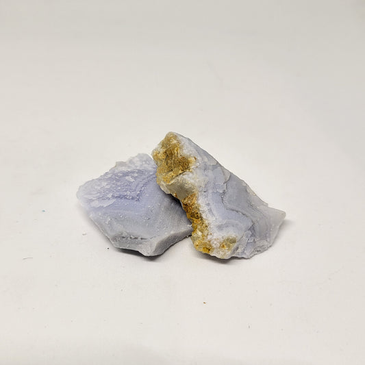 A raw Blue Lace Agate stone with a lace-like pattern against a white background.