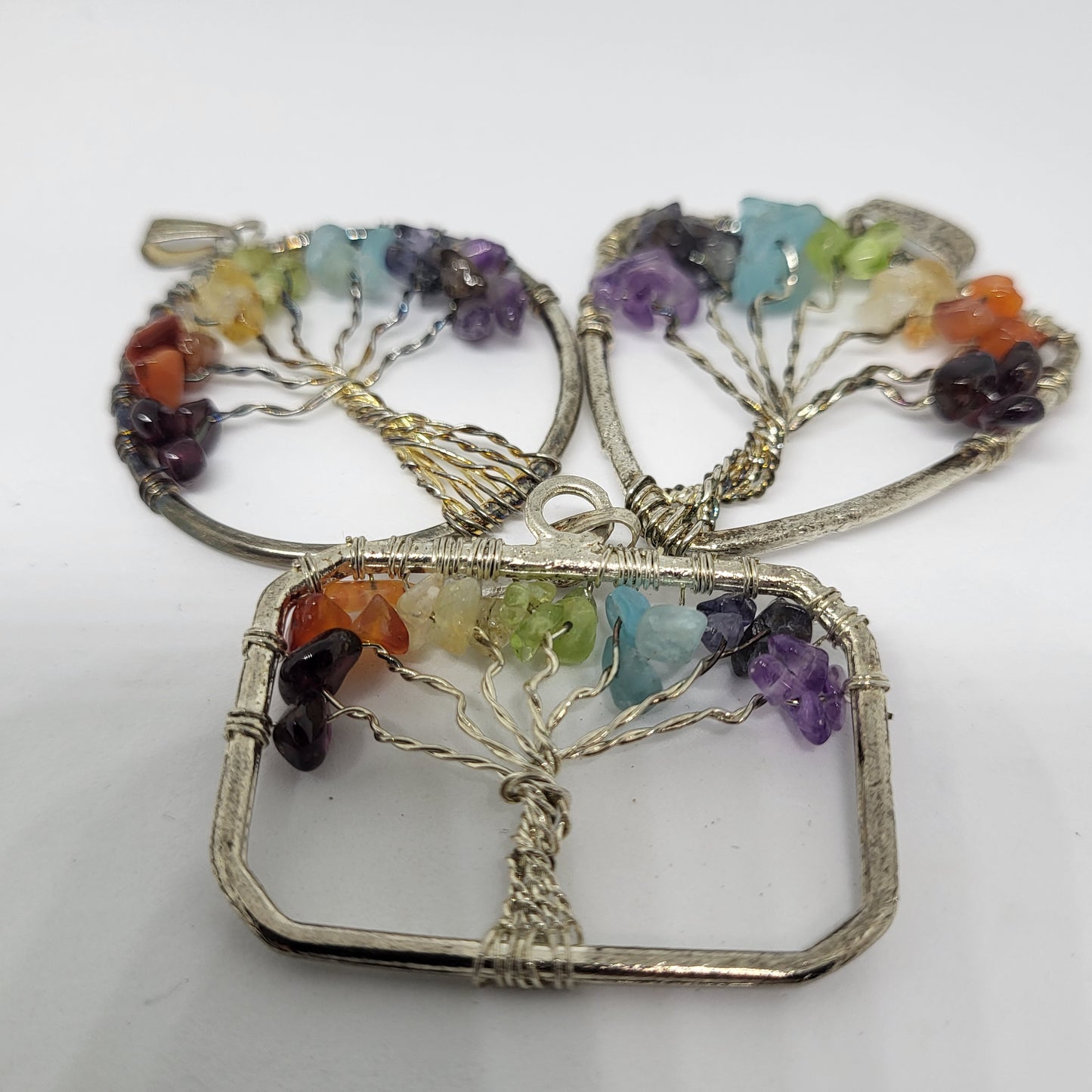 A pendant featuring a silver wire Tree of Life design with multiple colorful gemstones on its branches.