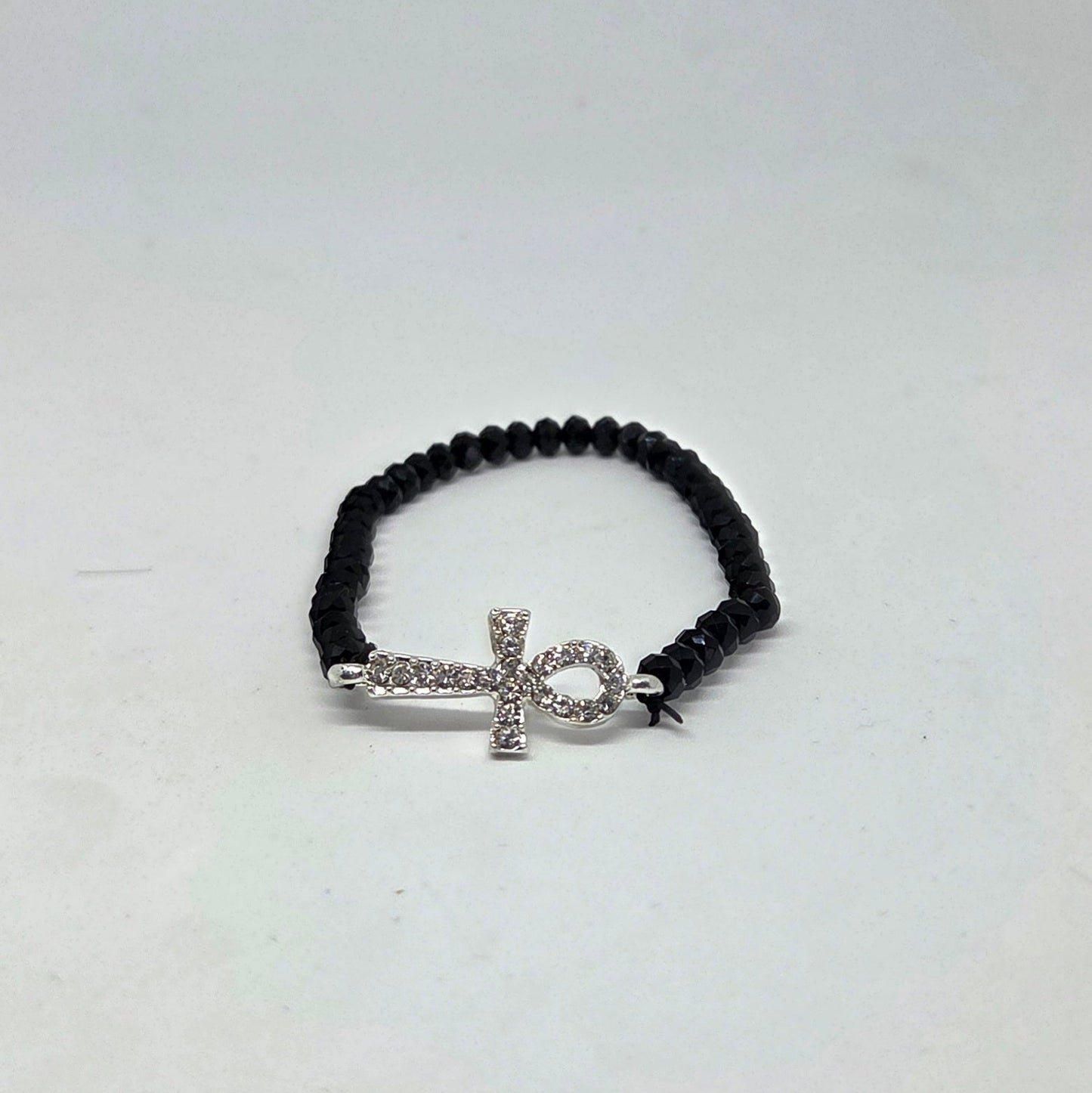 Black beaded bracelet with a silver cross charm on a white background