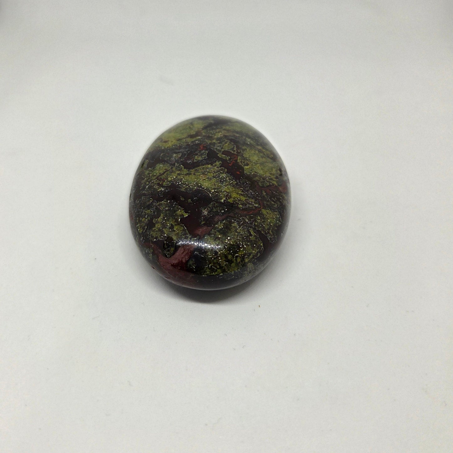 Oval-shaped stone with green and brown patterns on a white background