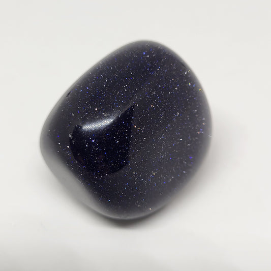 A polished Blue Goldstone gemstone with a sparkling appearance