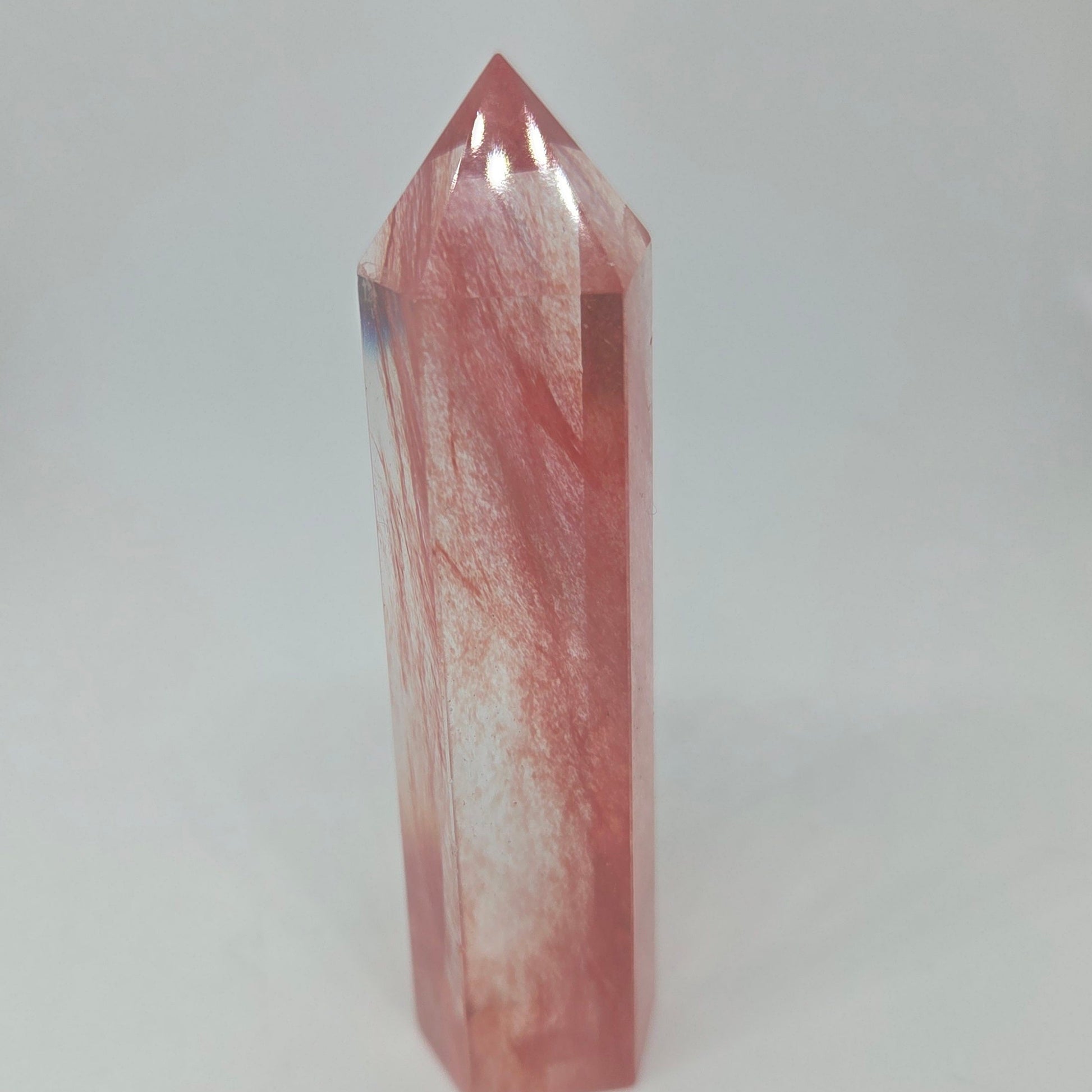 Polished energy cherry quartz crystal tower standing upright.