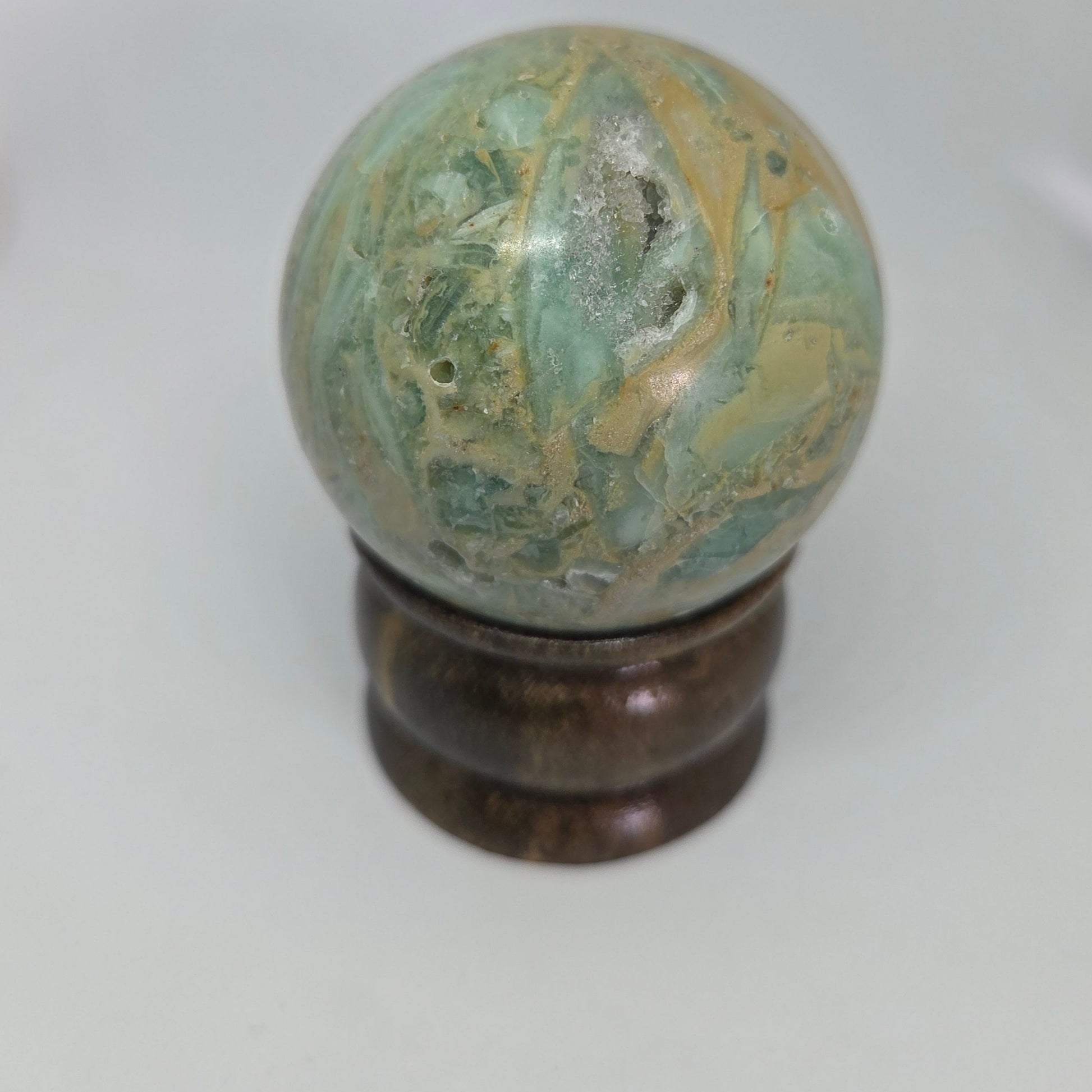 Marble-like sphere on a wooden stand against a white background