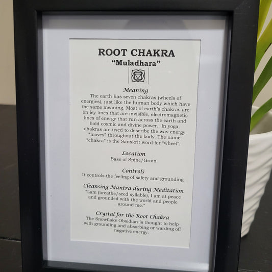 An informational print about the Root Chakra 'Muladhara' displayed in a frame, including text on its meaning, location, cleansing mantra, and control. The print is accompanied by a Snowflake Obsidian crystal.