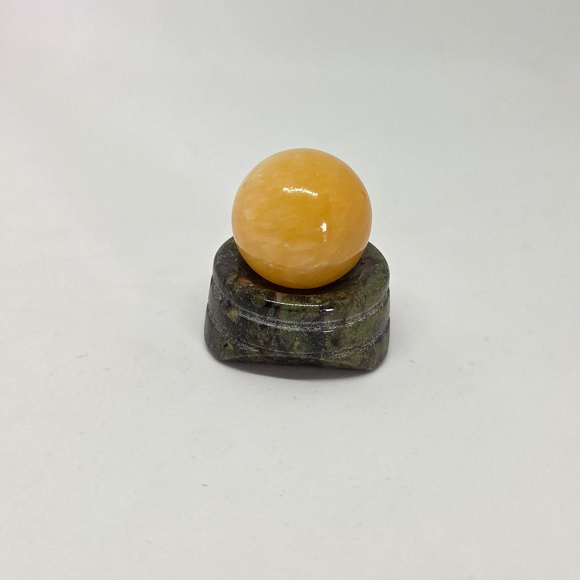 Yellow sphere on a dark green base against a white background