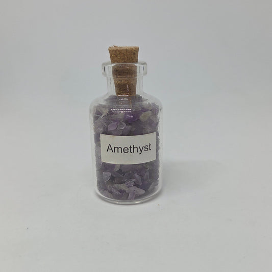 Small glass bottle filled with amethyst crystals on a white background