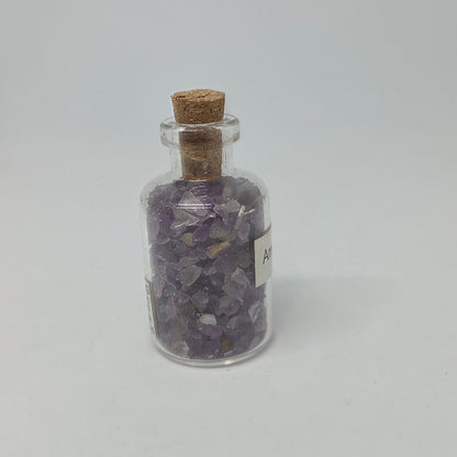 Glass jar with cork lid containing purple crystals on a white background