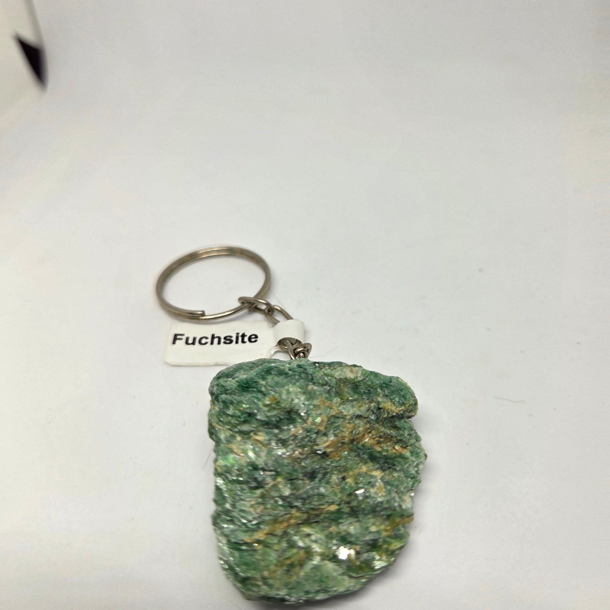 Green mineral specimen with a keychain labeled 'Fuchsite' on a white background