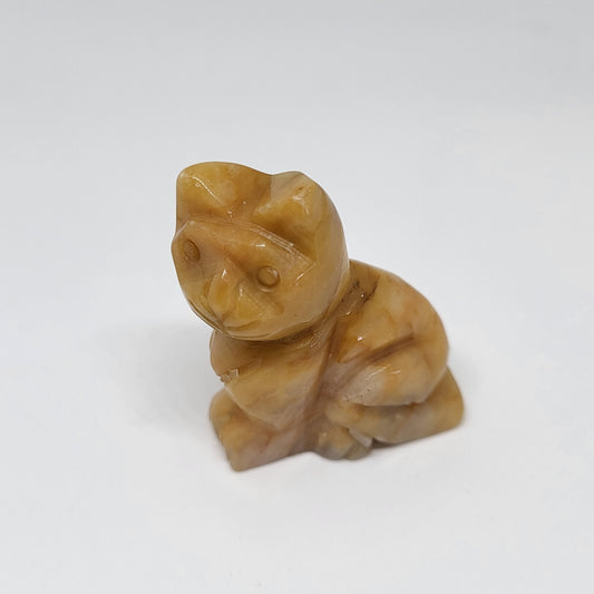 A small carnelian stone figure shaped like a cat, with shades of red, orange, brown, and pink.