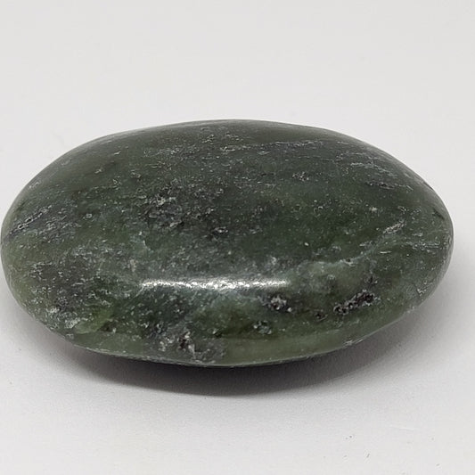 A polished nephrite jade palm stone on a white background.
