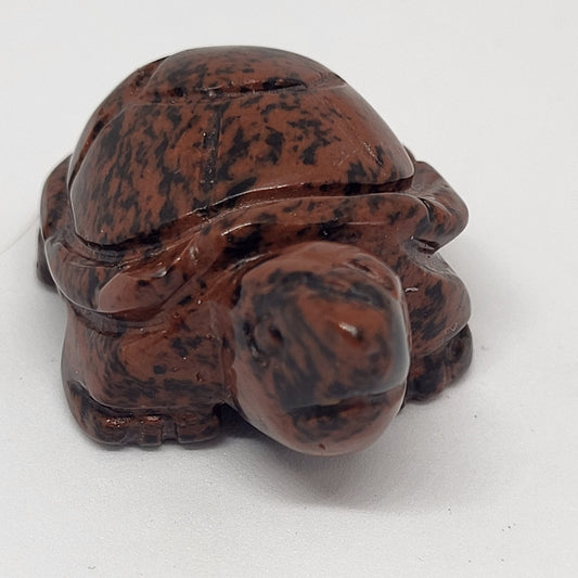 A small figurine of a turtle made from mahogany jasper stone, displaying a mottled pattern of colors including black, brown, and gray.