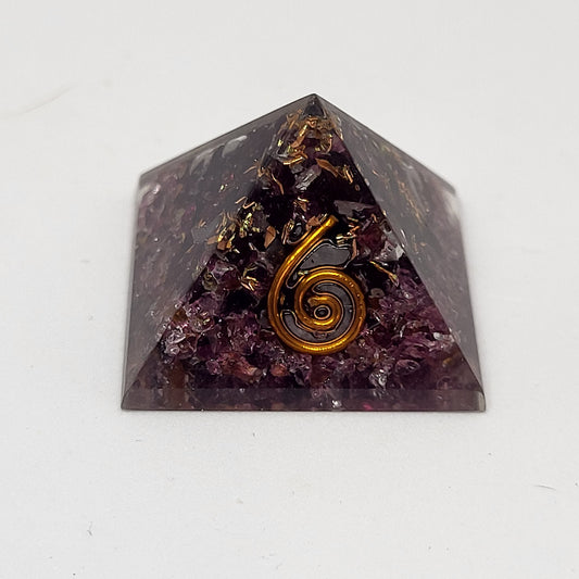 A garnet and organite mini pyramid with a spiral design on top, used for meditation and as a decorative piece.