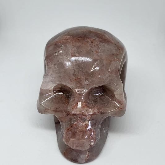 A large, polished Fire Quartz crystal shaped like a skull, displaying various shades of orange, brown, and red.
