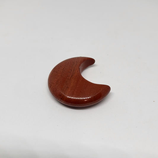 A small red jasper stone shaped like a crescent moon against a white background.
