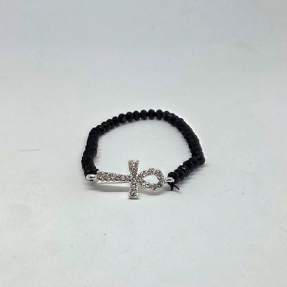 Black beaded bracelet with a silver cross charm on a white background