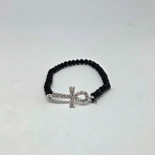 Black beaded bracelet with a silver cross charm on a white background