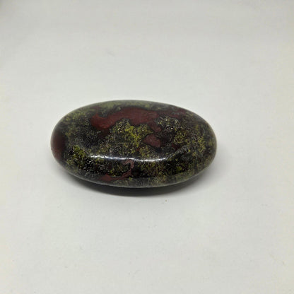 Oval-shaped stone with green and red patterns on a white background