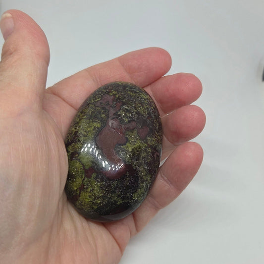 Hand holding a polished stone against a white background