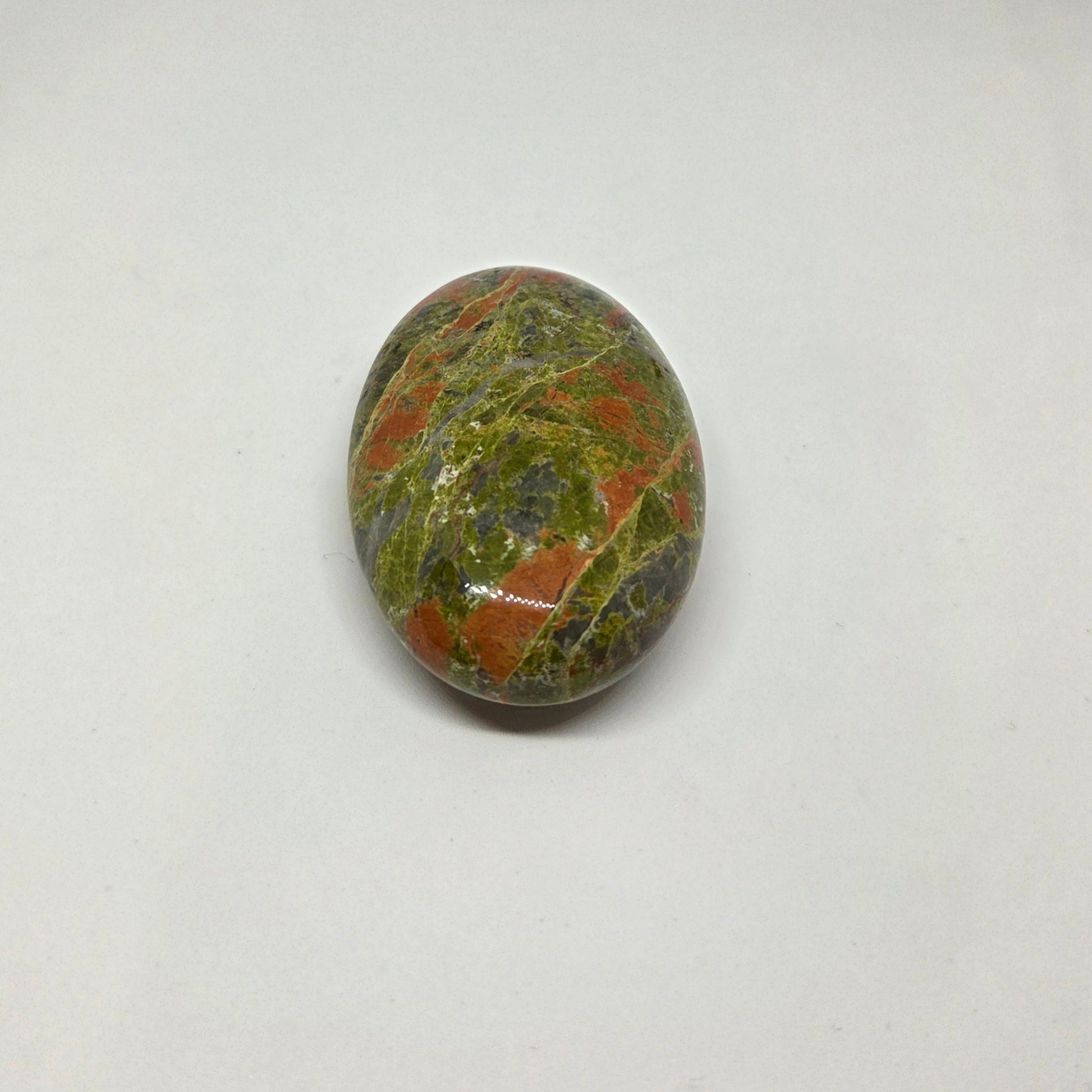 Oval-shaped gemstone with green, brown, and black patterns on a white background