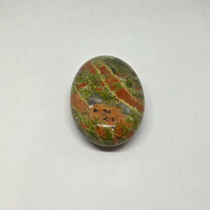 Oval-shaped stone with green and brown patterns on a white background