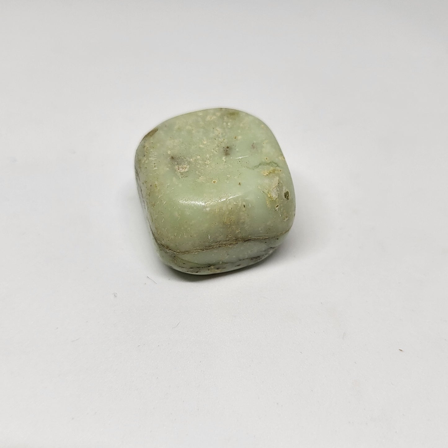 A polished chrysoprase stone with a pale green color